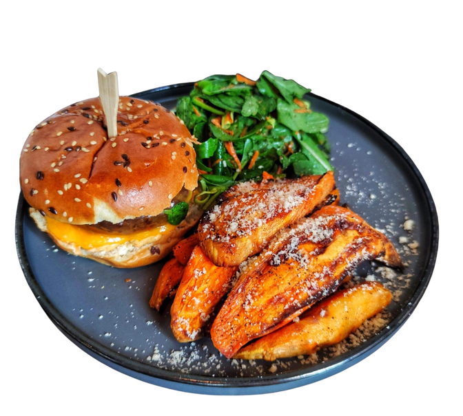 O farfurie apetisantă cu un burger suculent cu brânză, cartofi dulci copți presărați cu parmezan și o salată proaspătă cu verdețuri și morcov ras.